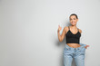 © New Africa - Slim woman in oversized jeans on light background, space for text. Weight loss