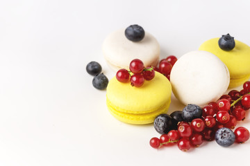 Wall Mural - French Colorful Macarons White and Yellow Macarons on Blue Background with Fresh Red Currant Copy Space Horizontal French Dessert