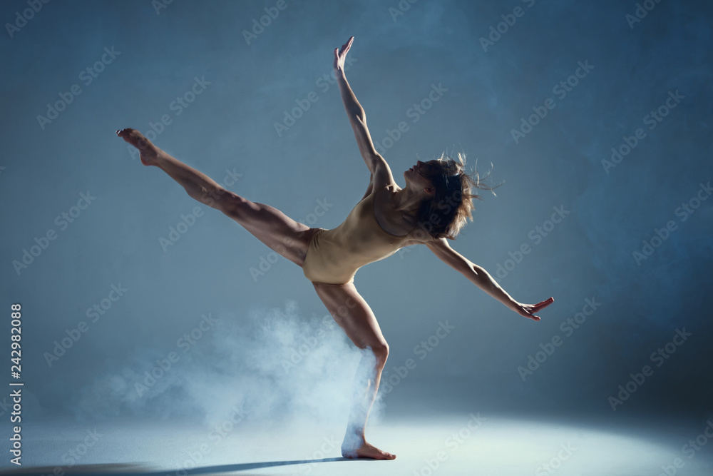 Dancing in cloud concept. Muscle brunette beauty female girl adult woman dancer athlete in fog smoke fume wearing dance bodysuit making stretches dance element performance on isolated grey background - obrazy, fototapety, plakaty 