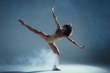 Dancing in cloud concept. Muscle brunette beauty female girl adult woman dancer athlete in fog smoke fume wearing dance bodysuit making stretches dance element performance on isolated grey background
