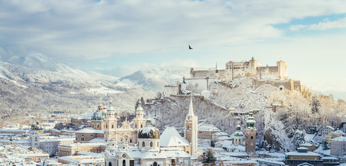 Wall Mural - Bird flying over Salzburg in winter: Snowy historical center, sunshine