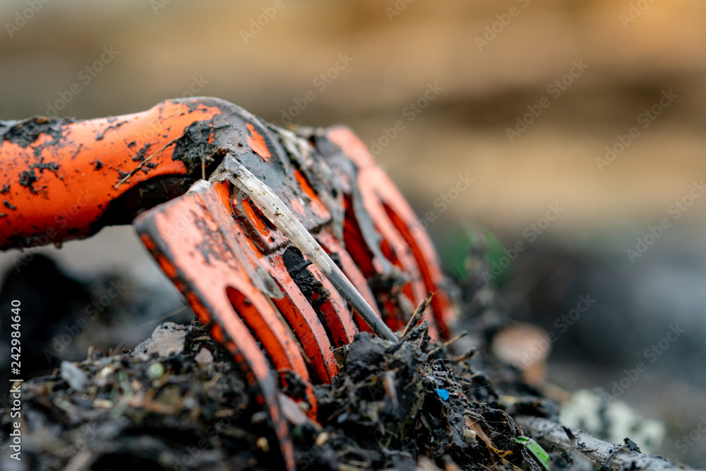 Closeup orange rake on pile of dirty plastic waste on blurred ...