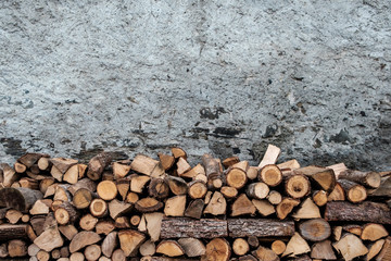 Fire wood, piled up and stored, ready for Winter, against an old, weathered stone wall, in the French alps