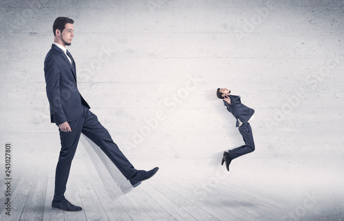 Fotografía Giant man kicking out small man from space with grungy background