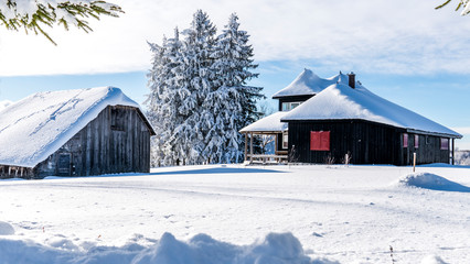 Mountain lodge in the picturesque Romania`s country side on a cold winter morning. Pristine clear ski  and snowy mountain peaks in the background. Piatra Craiului National Park.