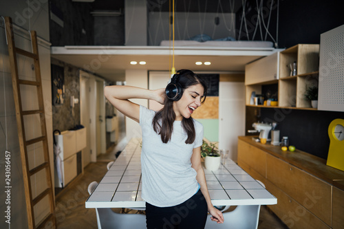 Fotografie, Obraz Cheerful woman listening to music with large headphones and singing