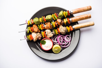 Wall Mural - Chicken Hariyali kakab or Malai malai kebab served with skewers and yogurt dip in a plate. selective focus