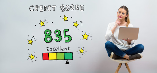 Wall Mural - Excellent credit score theme with young woman using her laptop on a grey background