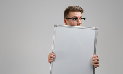 Part of young man wearing glasses with clean magnetic Board in his hands isolated on white background