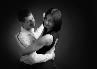 Young beautiful woman in black dress and man in white shirt dancing tango.