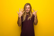 © luismolinero - Blond man with long hair over yellow wall counting seven with fingers