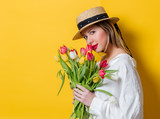 Fototapeta Tulipany - woman in white shirt and hat with fresh springtime tulips