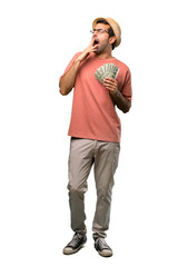 Man holding many bills yawning and covering wide open mouth with hand on isolated white background