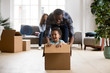 © fizkes - Cute little mixed race son laughing excited by riding in box with african dad on moving day, happy father plays with kid boy after relocation, black family and child have fun in new home living room