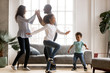 © fizkes - Happy african american family and funny active children having fun dancing together at new home, cheerful black parents and two kids enjoying moving to music spending weekend time in living room