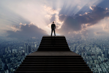 success and leader concept, businessman in suit standing on top of stair and looking over city with 