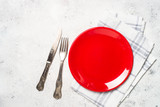 Fototapeta  - Red plate, cutlery and tablecloth on light stone table.