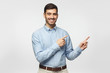 © Damir Khabirov - Happy smiling young business man pointing away, isolated on gray background
