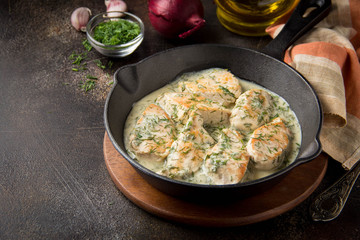 Canvas Print - Chicken fillet or Turkey breast in creamy sauce with dill and garlic, in cast iron black pan on dark background. Delicious homemade food