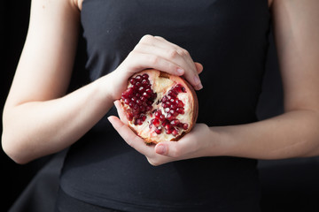 Woman hands holding a pomegranate on the black background