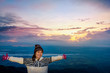 © yongkiet - Woman tourist in a sweater standing outstretched arms, happy while watching the beautiful nature landscape of the forest and mountain during the sunrise at Phu Thap Boek Viewpoint Phetchabun, Thailand
