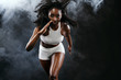 © Mike Orlov - Strong athletic black skin woman sprinter, running on background with smoke wearing in the sportswear. Fitness and sport motivation. Runner concept with copy space.