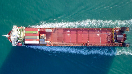 Large Cargo and RoRo (Roll On-Off) ship at sea, loaded with a small amount of shipping containers and two large cranes - Aerial image.