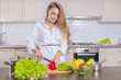 © fotoplaton - Beautiful girl in a white shirt prepares vegetables in the kitchen