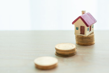 Selective focus miniature small house with golden coins with copy space, real estate business investment, loan from a bank for housing.