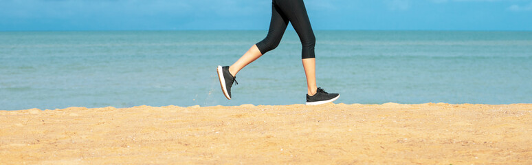 Wall Mural - Running woman. Female runner jogging during outdoor workout on beach. Fitness model outdoors. Feet of young woman jogging on the beach. Fitness female on morning run at sea shore