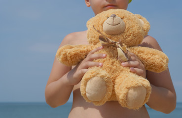 little boy with teddy bear on the beach