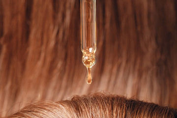 Close-up drop of oil restore and recovery hair is applied to head bulbs. Concept hairdresser spa salon