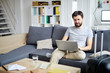© pressmaster - Young casual man with laptop sitting on sofa and searching for online travel offers before vacation