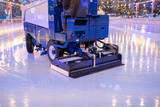 Fototapeta Sypialnia - A machine for restoring or smoothing ice rides on an ice rink in the evening.