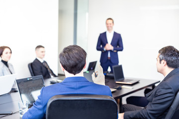 Wall Mural - Colleague asking a question to businessman during a presentation. Successful team leader and business owner leading informal in-house business meeting. Business and entrepreneurship concept.