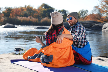 Wall Mural - Campers sitting in sleeping bags on wild beach