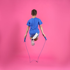 Active boy jumping rope on color background