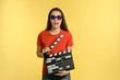 Woman with 3D glasses and clapperboard on color background. Cinema show
