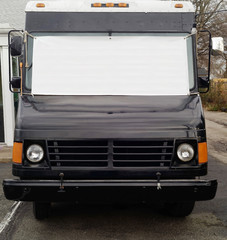 Wall Mural - Front view of stationary black food truck with blank white banner stretched across windshield. Copy space.