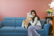 © saksit - Portrait of young asian woman holding  her dog chihuahua on sofa at home.