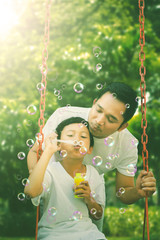 Wall Mural - Child blowing soap bubbles with his father