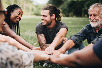 Happy people stacking hands together in the park