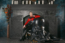 Beautiful Woman In Black Latex With Red Breasts Posing Against The Fireplace In The Gothic Deluxe Room With White Candles And Big Octopus