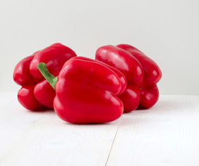 Wall Mural - Three red peppers on a wooden white table