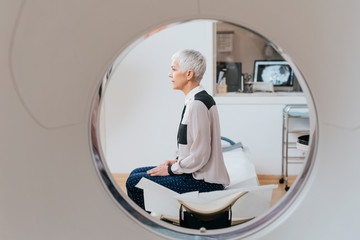 Wall Mural - Woman Sitting on a CT Scanner Bed