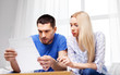 © Syda Productions - family budget, savings and people concept - couple with paper bill at home