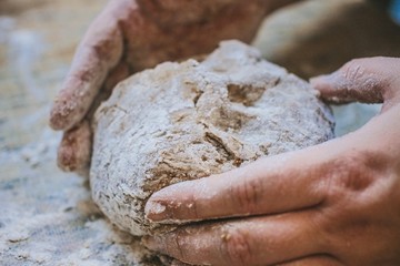 Female hands cook kneaded a piece of dough on the table, flour everywhere