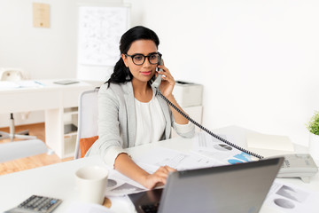 Wall Mural - business, communication and people concept - happy smiling businesswoman with laptop computer and papers calling on desk phone at office