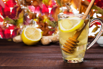 Autumn hot tea warming drink with ginger, honey and lemon in glass on wooden background. Copy space. Food background