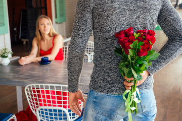 surprised blonde woman and handsome blond man at restaurant.happy couple romantic date, celebrating valentine day male model give red rose to his girl